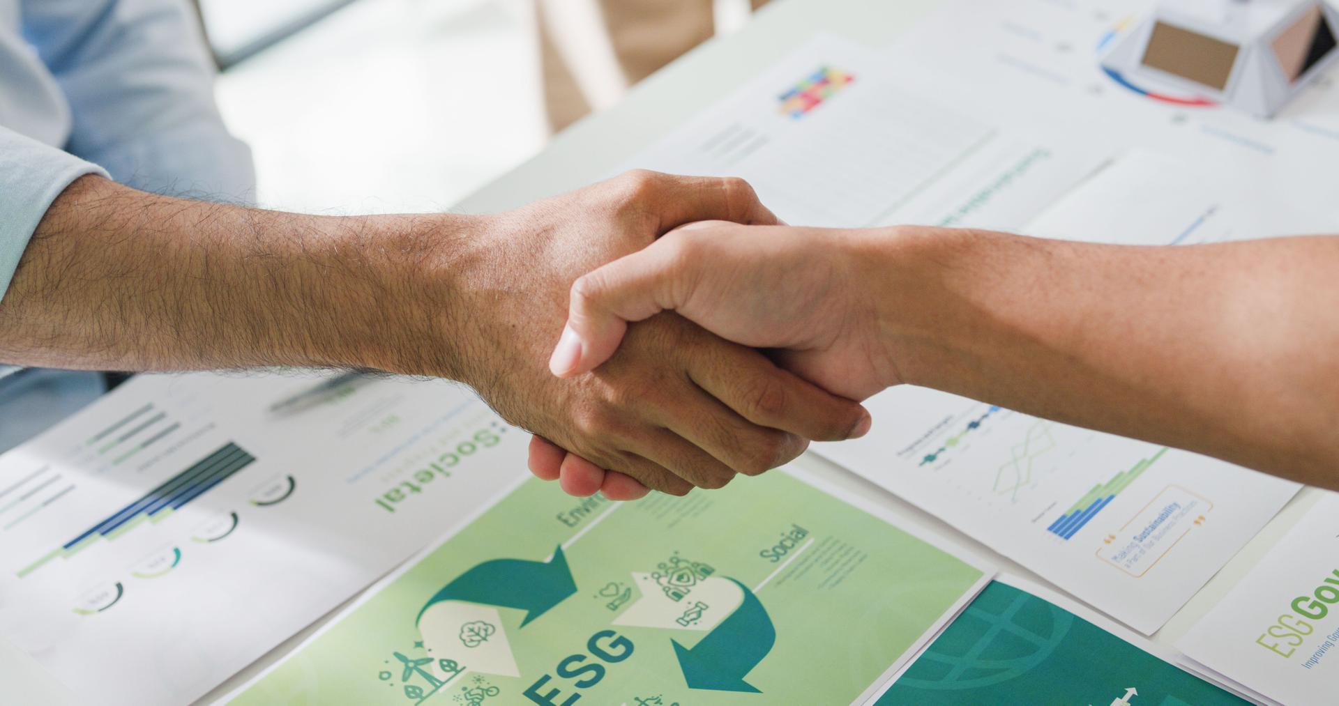 Closeup businesspeople shaking hands over ESG strategic commitment workshop, SDGs report, global warming, green finance investment eco friendly and net zero waste in boardroom training building.